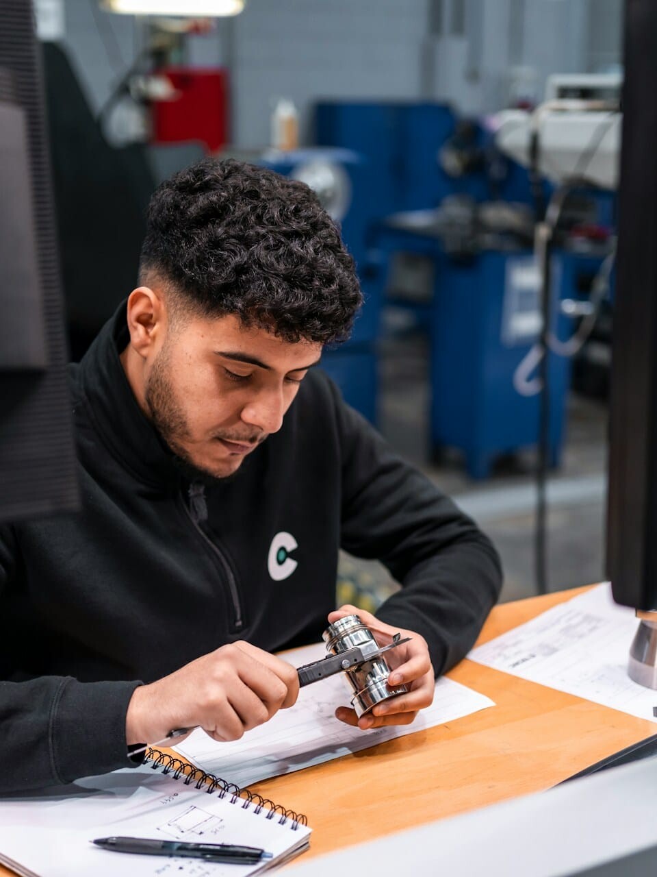 technician measuring with a caliper uai