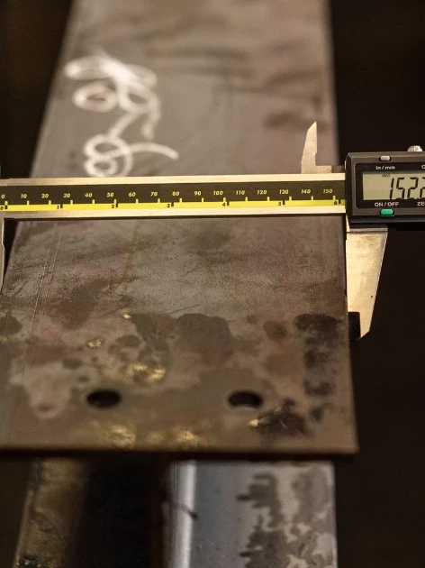 Digital caliper measuring a steel beam, illustrating the calibration compliance insurers look for in liability claims