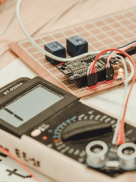 Technician verifying calibration in new product introduction with a handheld multimeter during electrical testing.
