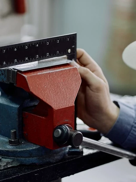 Machinist measuring a metal part in a production line vise, illustrating the cost of downtime in manufacturing when an instrument drifts out of tolerance
