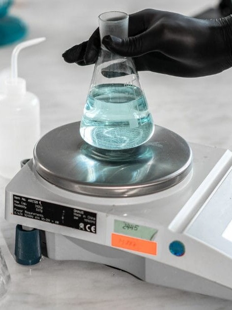 ISO 17025 weight calibration lab technician placing a flask on a precision balance scale