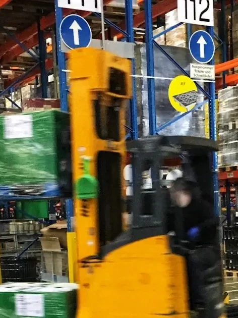 Warehouse forklift moving pallets, representing the pickup and delivery logistics behind calibration equipment shipping
