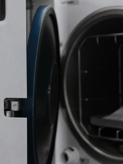 Open autoclave chamber with sterilized tray visible, showing the door seal checked during autoclave calibration