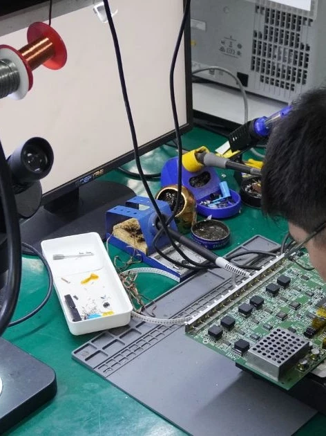 Technician preparing to calibrate new equipment on a circuit board before installation, using a bench microscope and soldering station