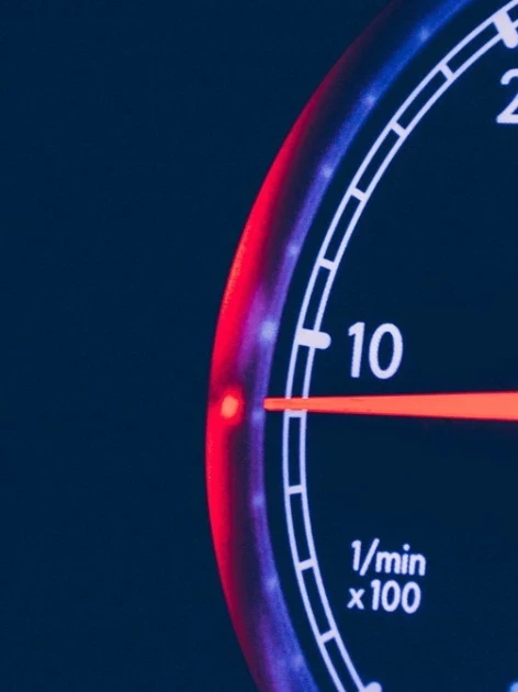 Close-up of a digital tachometer gauge with a glowing red RPM needle — the type of instrument verified during tachometer calibration