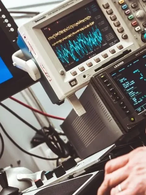 Technician using an oscilloscope probe to test signal waveforms on a calibration lab bench